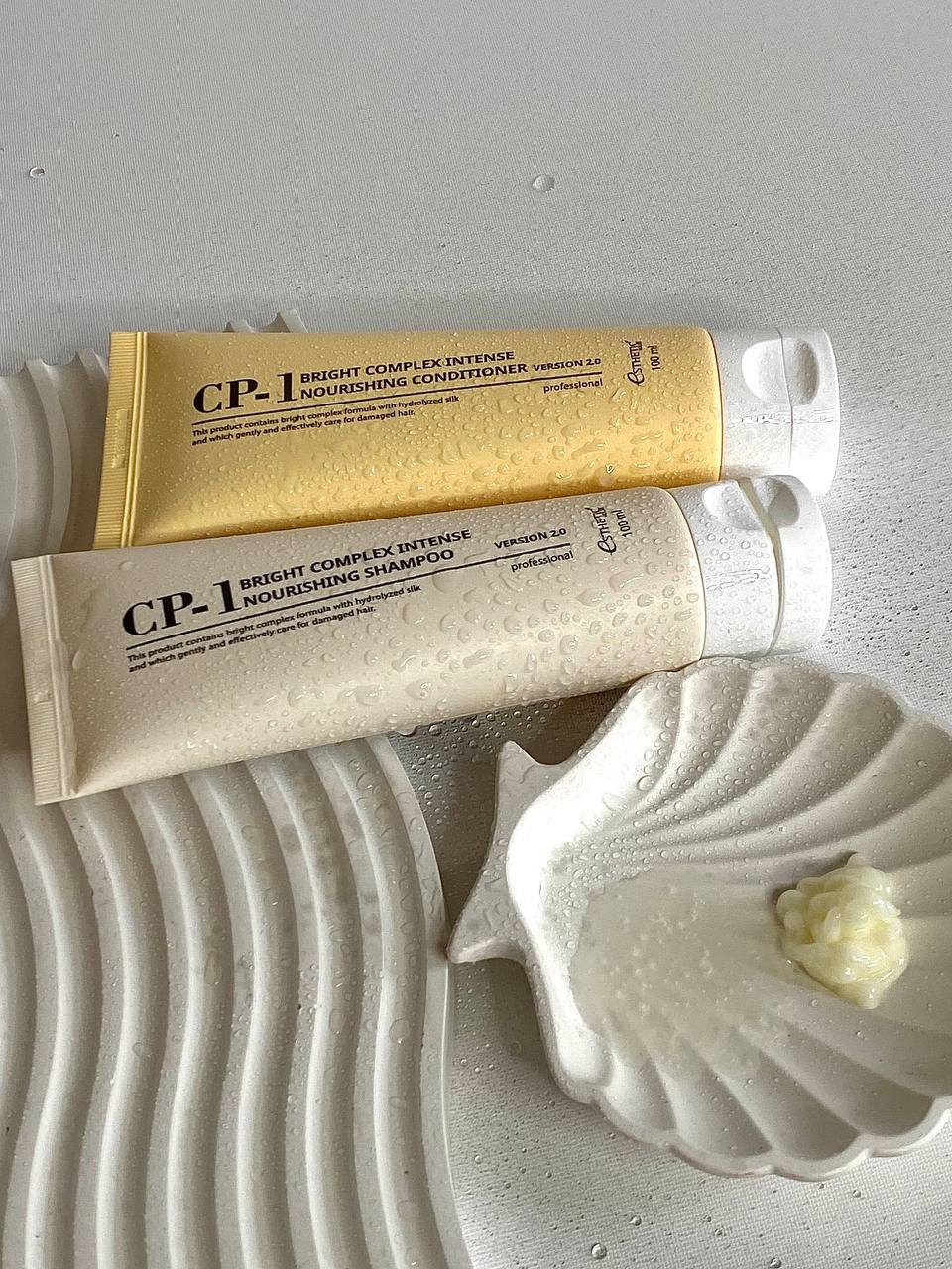 CP-1 Bright Complex Intensive šampūns un kondicionieris mini iepakojumos uz gaiša fona, blakus neliels krēma paraugs trauciņā
