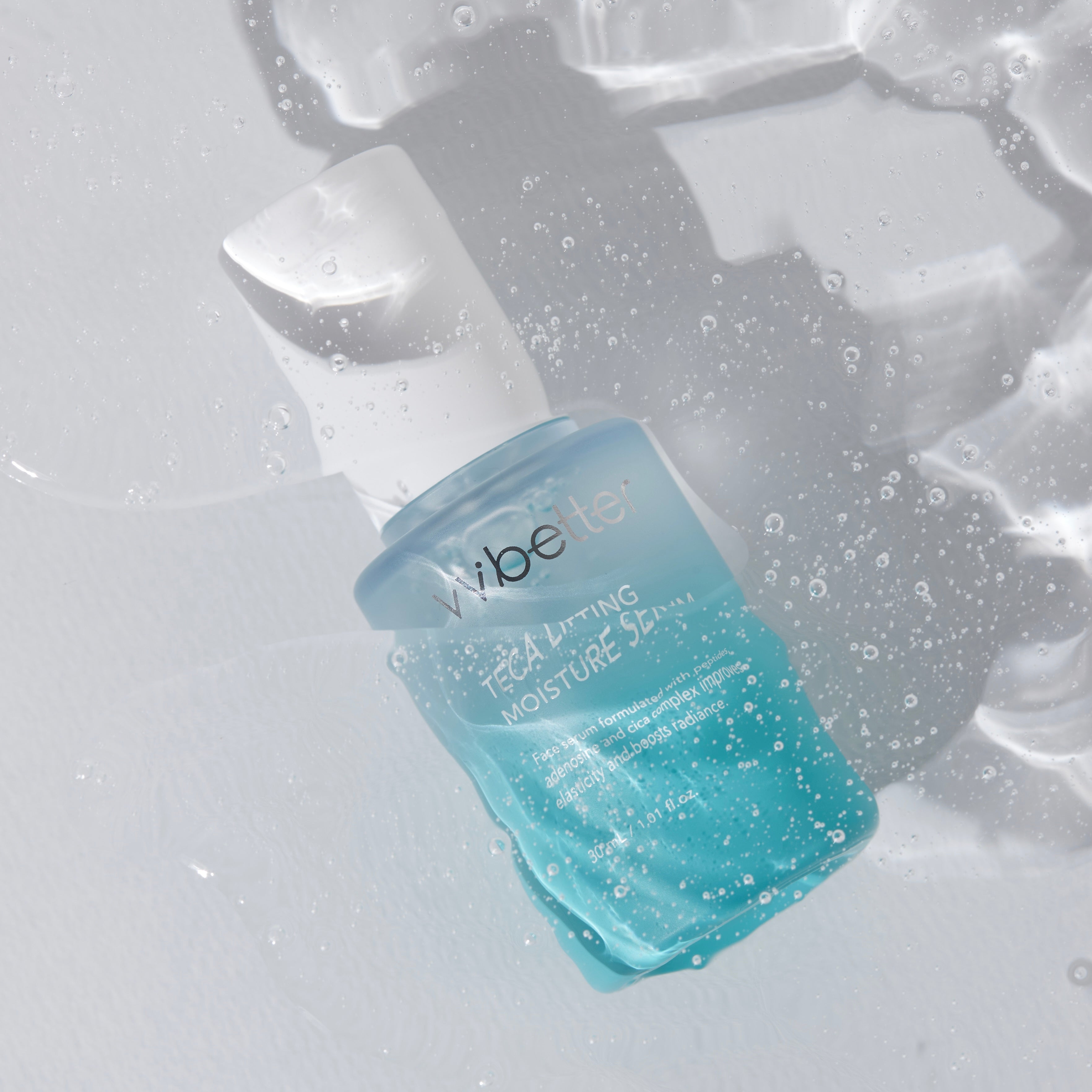 VVbetter TECA Lifting mitrinošais serums ar pipeti uz ledus gabaliņiem, ar ūdens pilieniem.